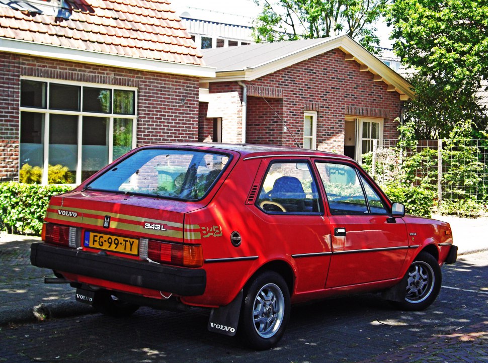 Red compact hatchback with angular rear, alloy wheels, and mudflaps
