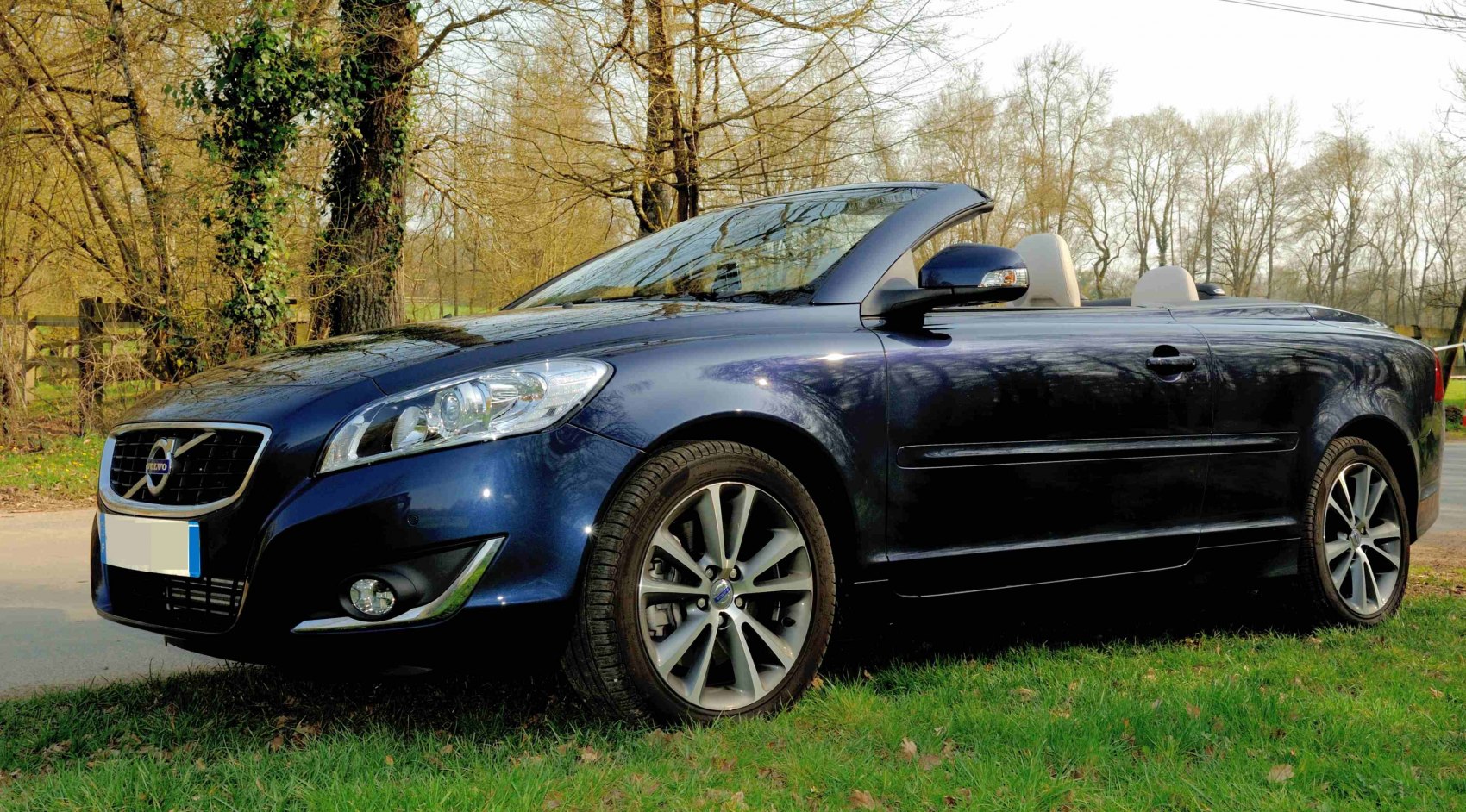 Convertible car with open roof and alloy wheels parked on grass