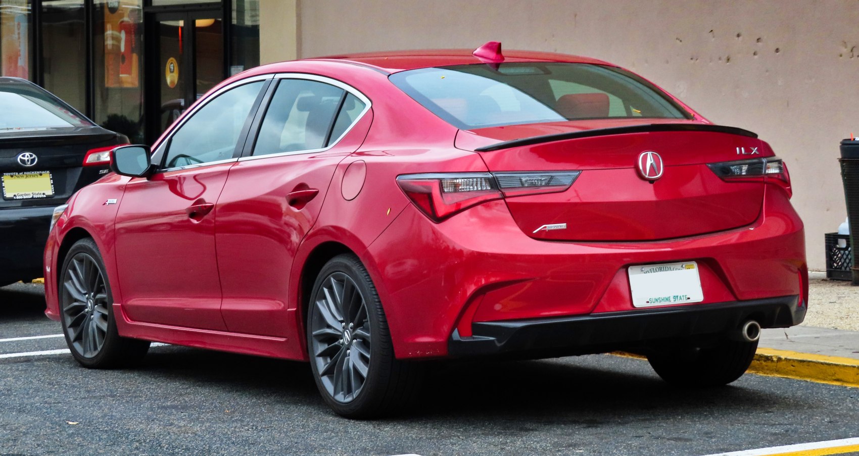 Rear side view of red sedan with spoiler and sporty alloy wheels