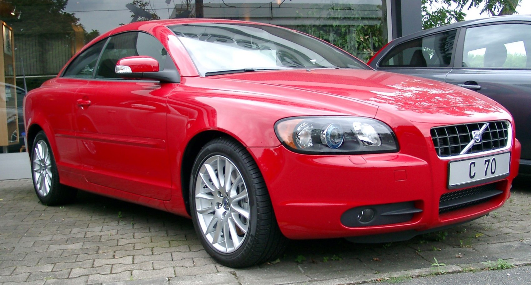 Front-side view of red sporty coupe with alloy wheels and clear headlights