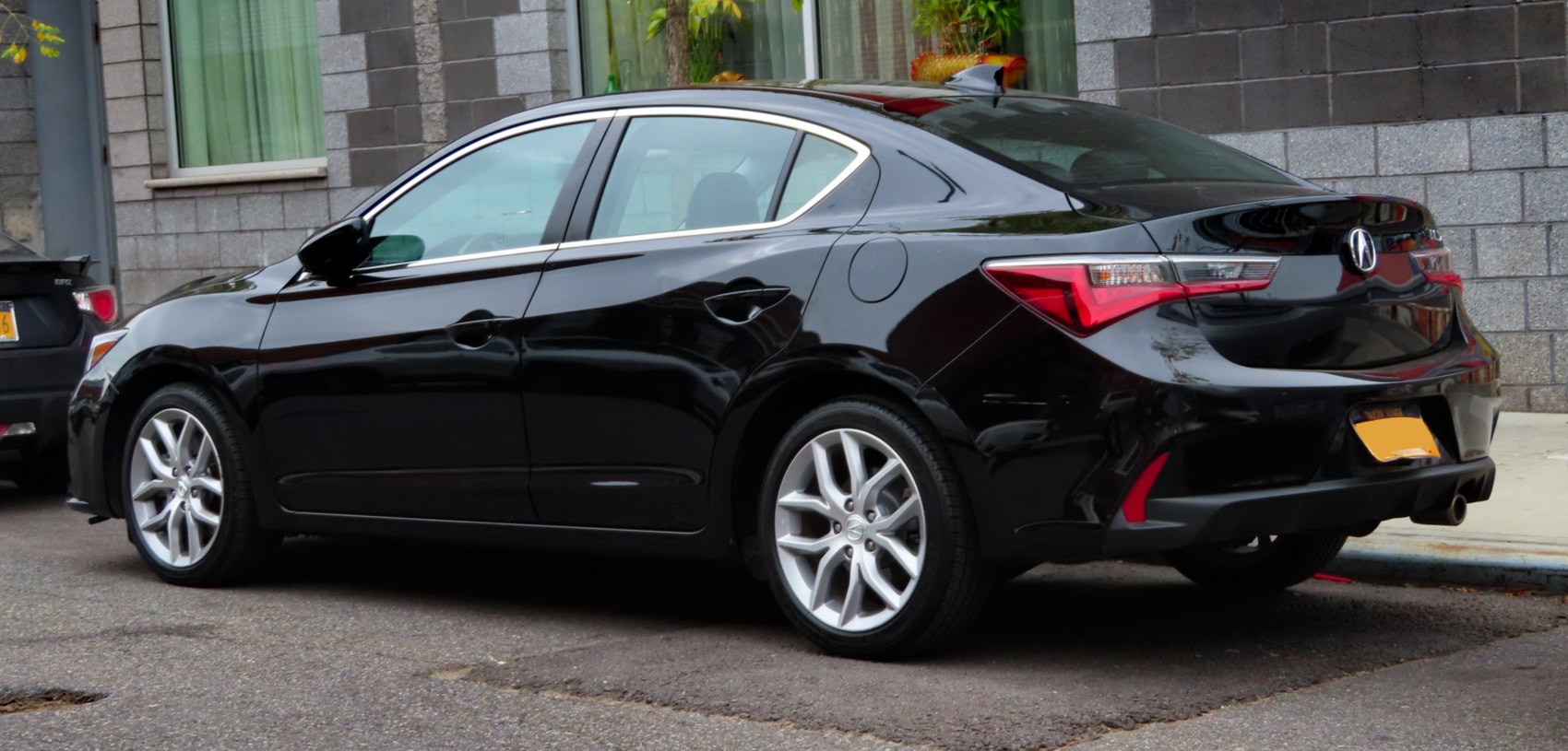 Rear and side view of a sleek black sedan with sharp tail lights.