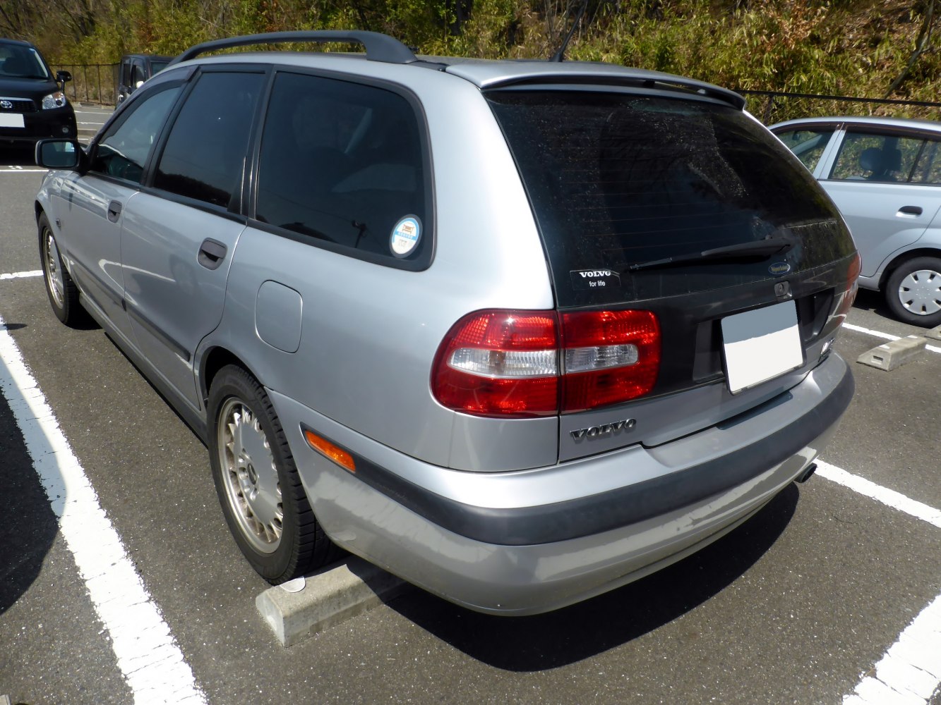 Rear view of a 1990s station wagon with tail lights and roof spoiler