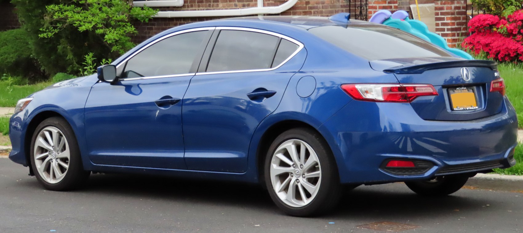Side and rear view of blue sedan with alloy wheels and tinted windows
