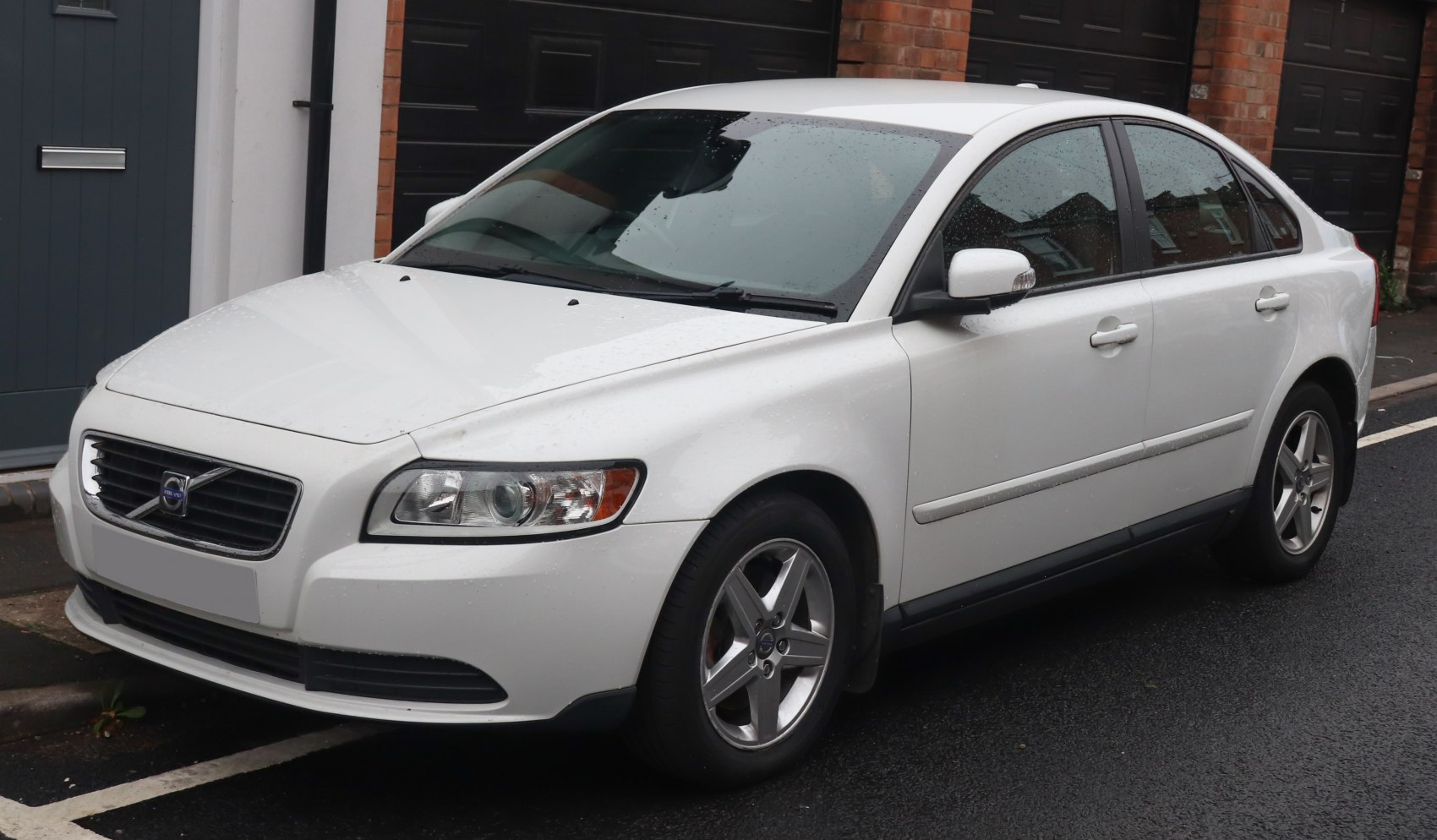 White sedan showing front-side view with alloy wheels and grille