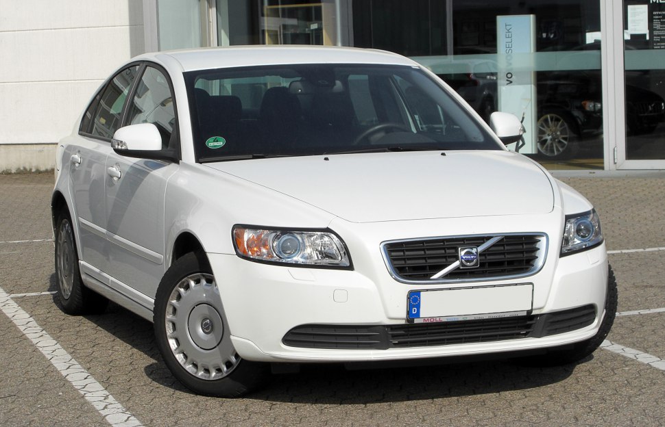 White sedan front grille and headlights on pavement