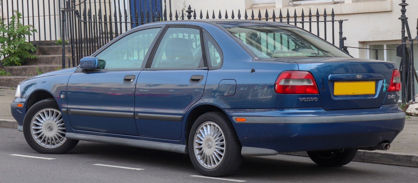Rear and side view of a blue mid-1990s sedan.