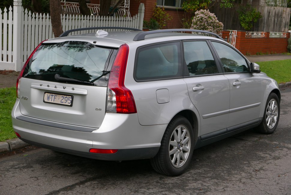 Rear side view of a silver station wagon with roof rails and distinctive vertical tail lights