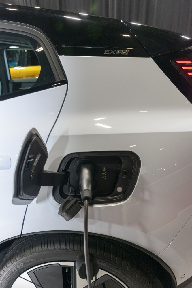 Electric vehicle charging port with cable connected on rear side panel.
