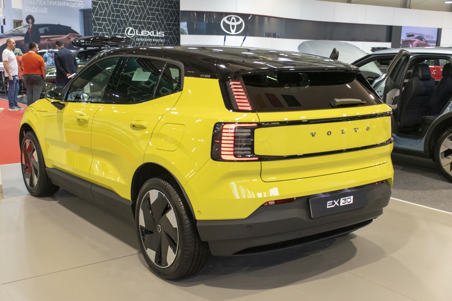 Rear view of an electric SUV with distinctive vertical LED taillights and two-tone yellow and black paint.