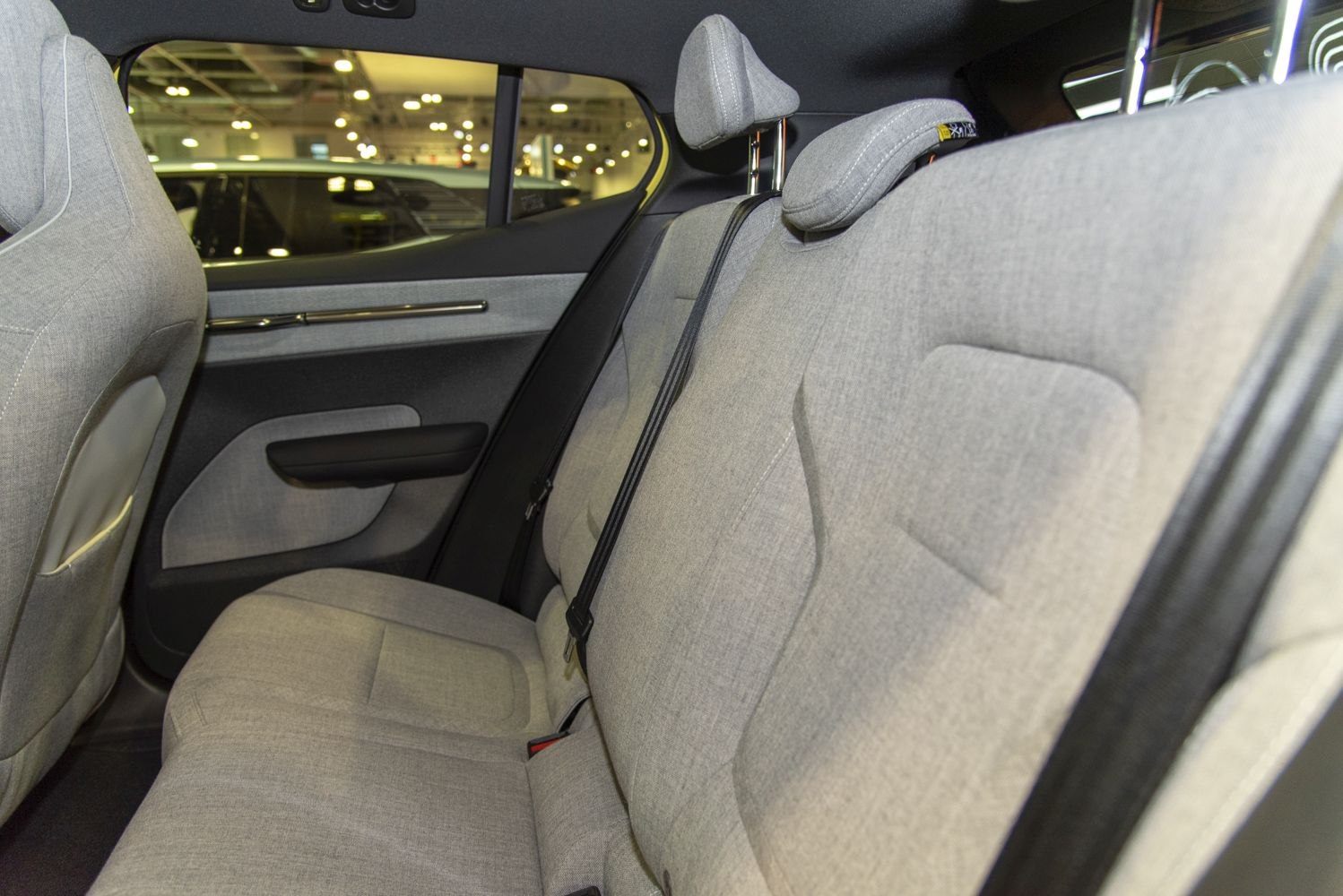 Rear car interior with light gray fabric seats and adjustable headrests