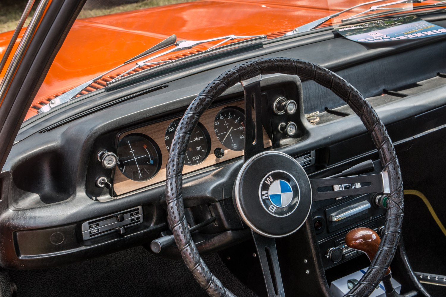 Vintage car steering wheel with leather wrap and retro dashboard gauges.