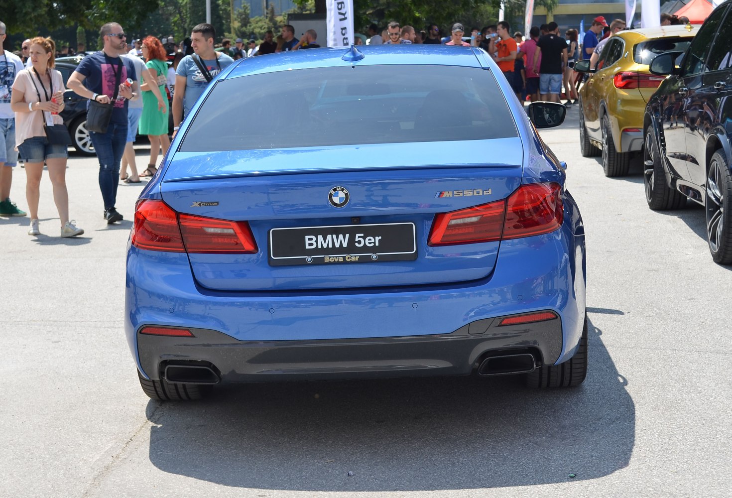 Rear view of blue luxury sedan with dual exhausts and prominent taillights