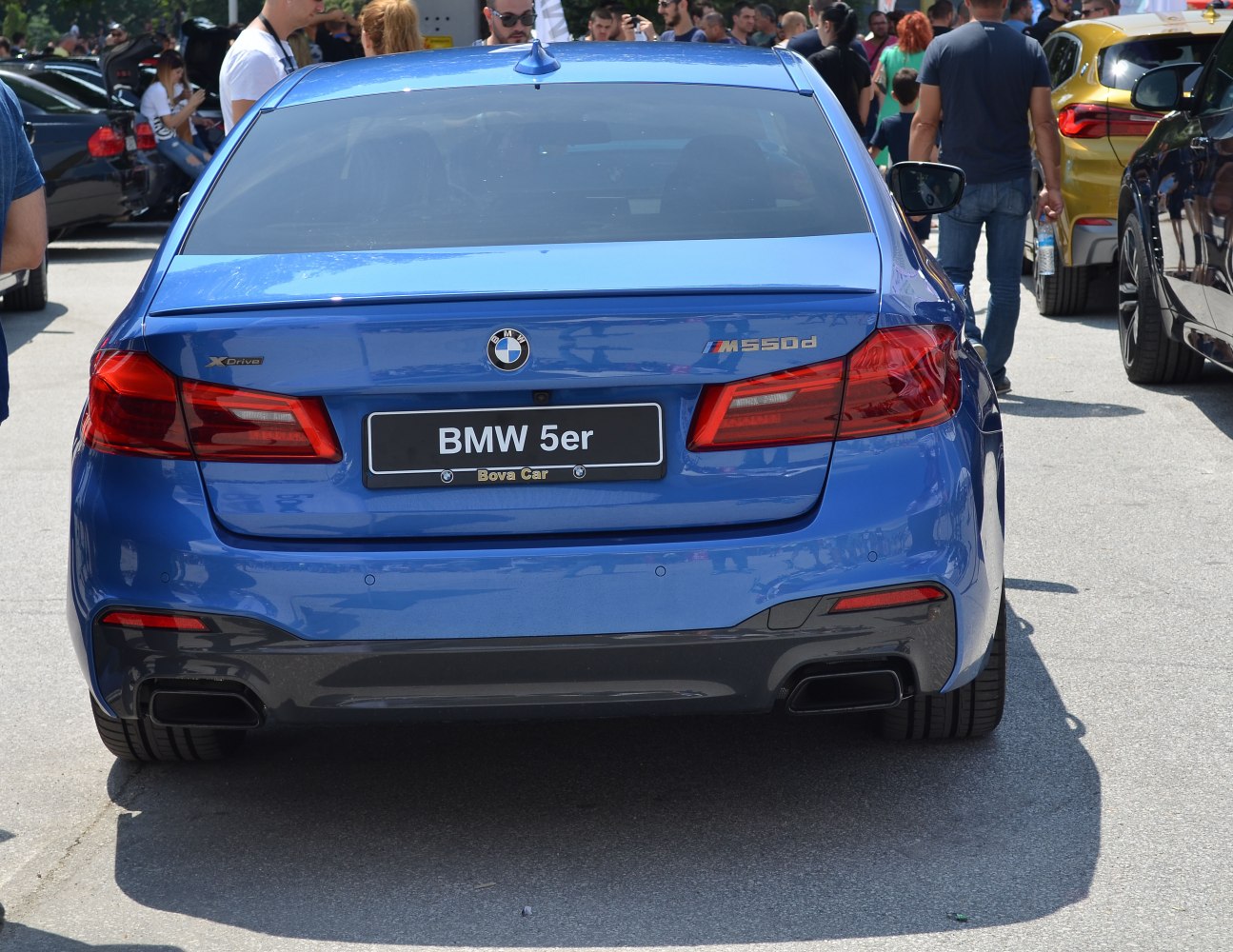Rear view of a blue sedan with distinct taillights and dual exhaust outlets