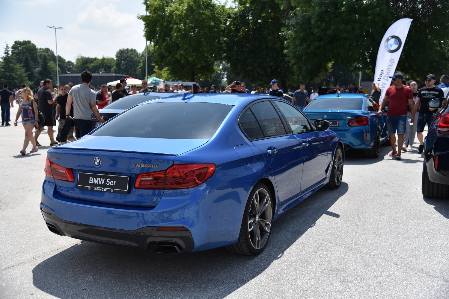 Rear view of blue luxury sedan with prominent taillights and quad exhaust