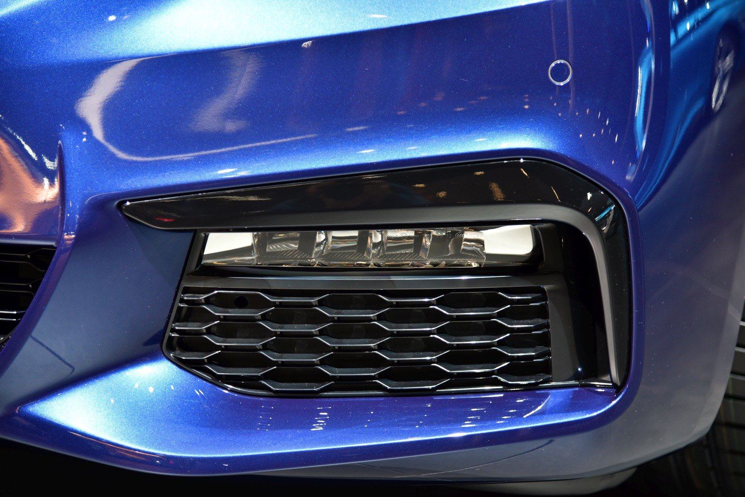 Close-up of front fog light and hexagonal air intake grille