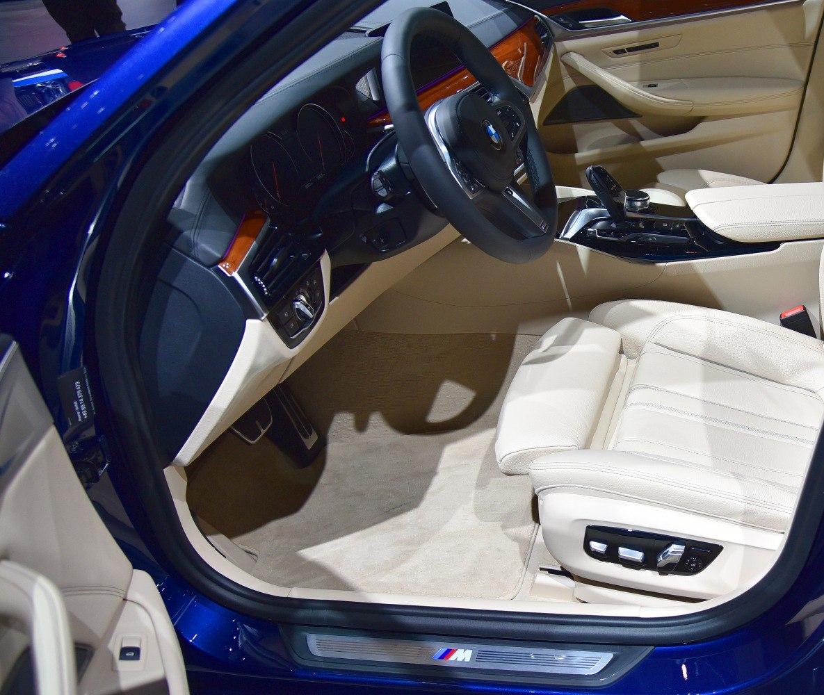 Luxury car interior with beige leather seats and advanced dashboard controls.