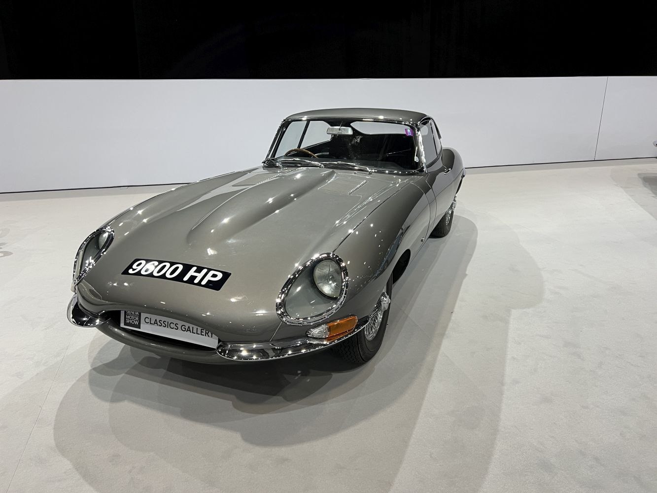 Silver metallic classic sports car with sleek elongated hood and distinctive headlights