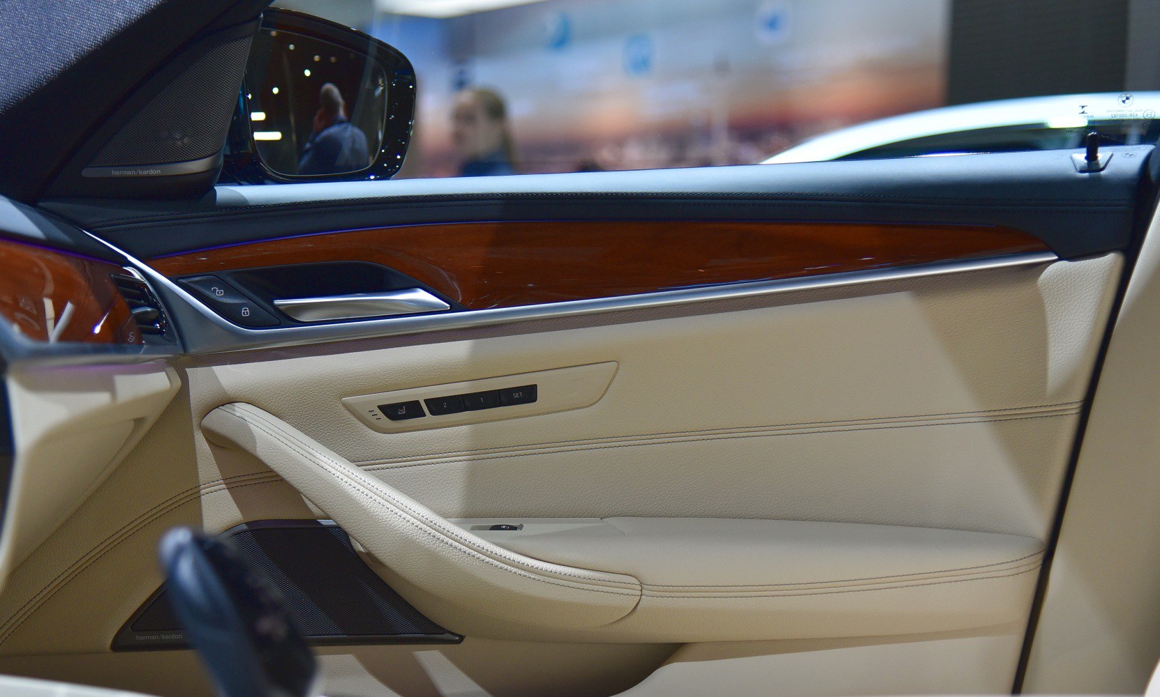 Car door interior with wood trim, beige leather, seat memory, and Harman Kardon speaker