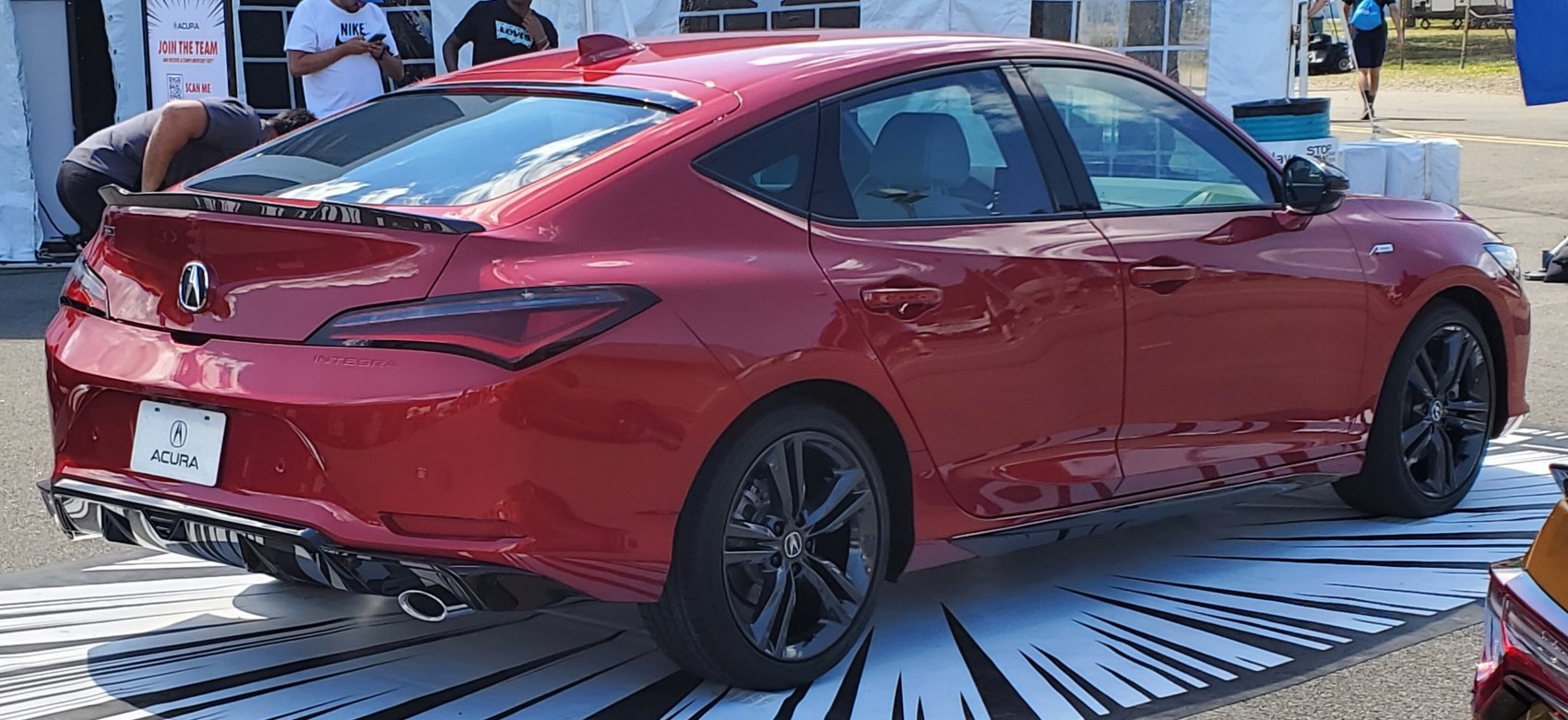 Rear and side view of red sporty sedan with rear spoiler and black alloy wheels