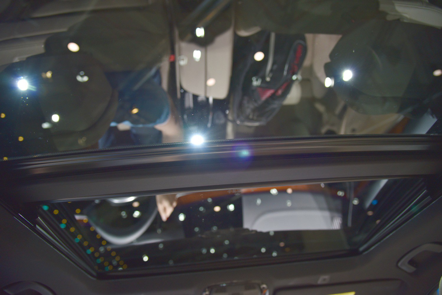 Panoramic sunroof view showing the car interior ceiling and reflections.