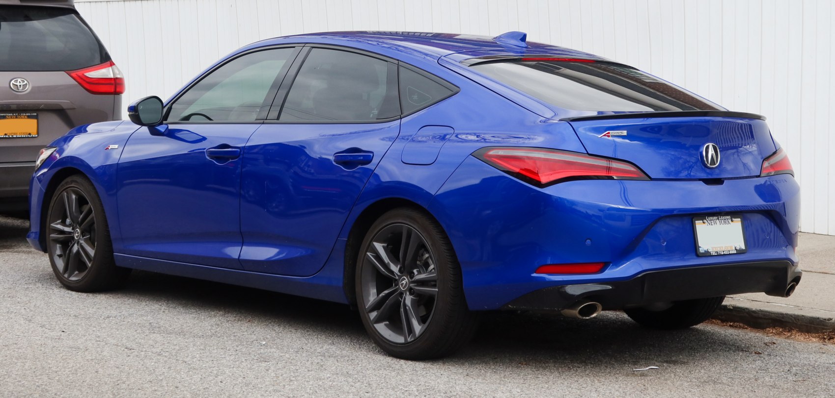 Rear side view of blue sedan with sporty tail lights and dual exhaust