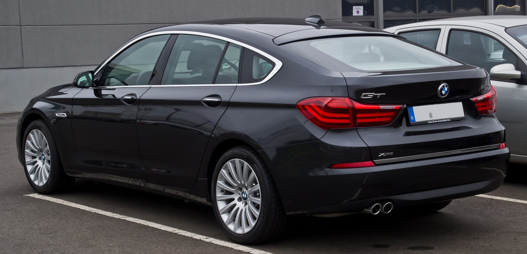 Rear view of luxury hatchback with GT badge, dual exhausts, and distinctive taillights.