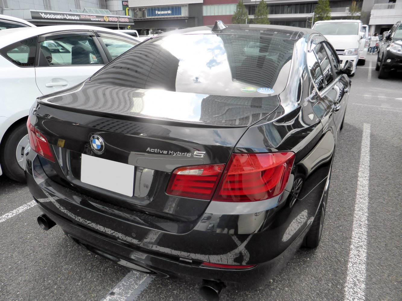 Rear view of black sedan with dual exhaust and hybrid badge