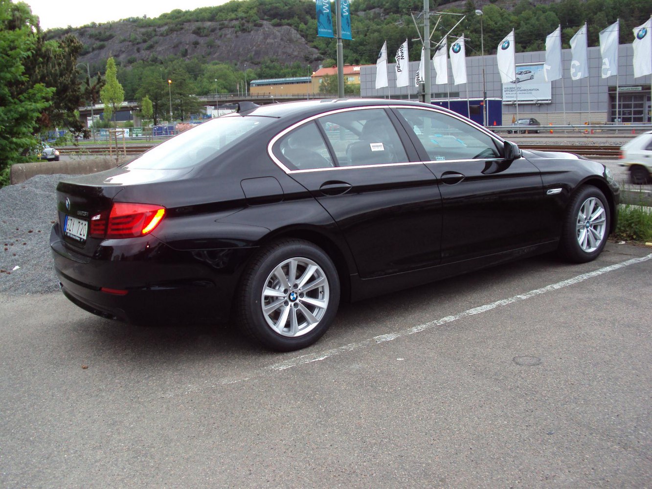 Rear side profile of a luxury sedan with distinctive tail lights and alloy wheels.