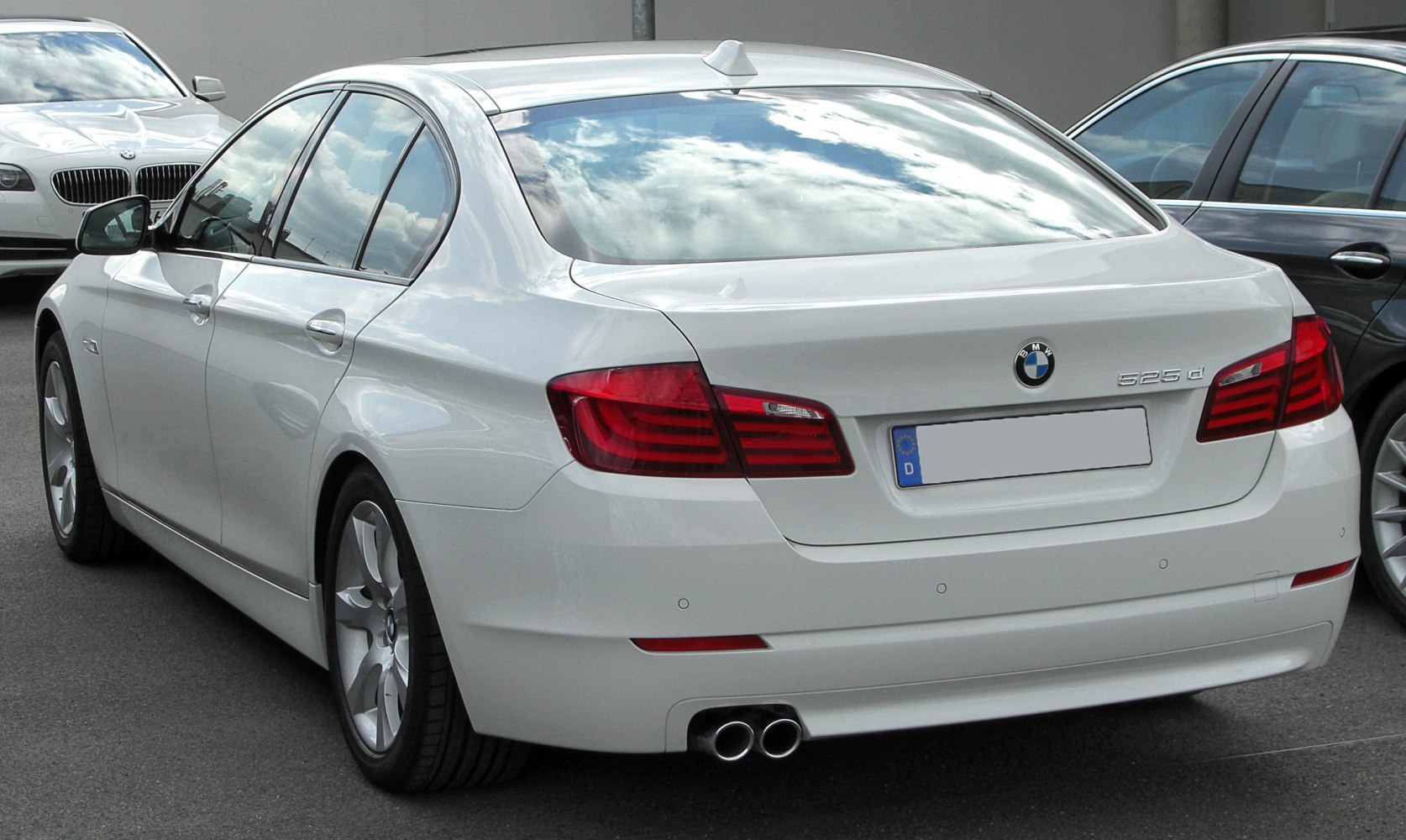 Rear view of white luxury sedan with dual exhaust and distinct taillights