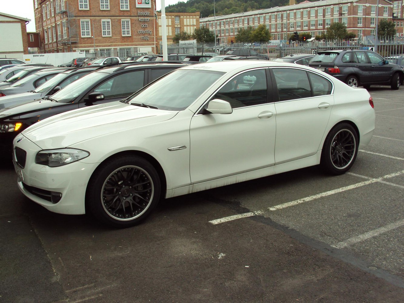 White sedan with dark multi-spoke alloy wheels side view