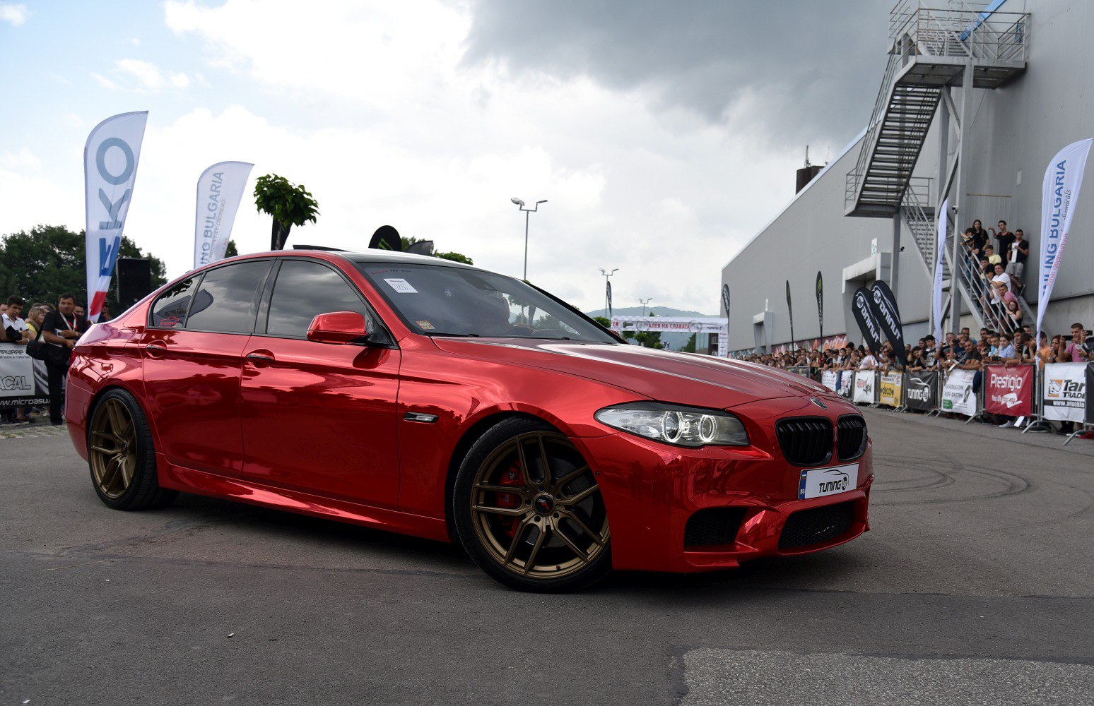 Red metallic sedan with sporty bronze rims and aggressive front fascia