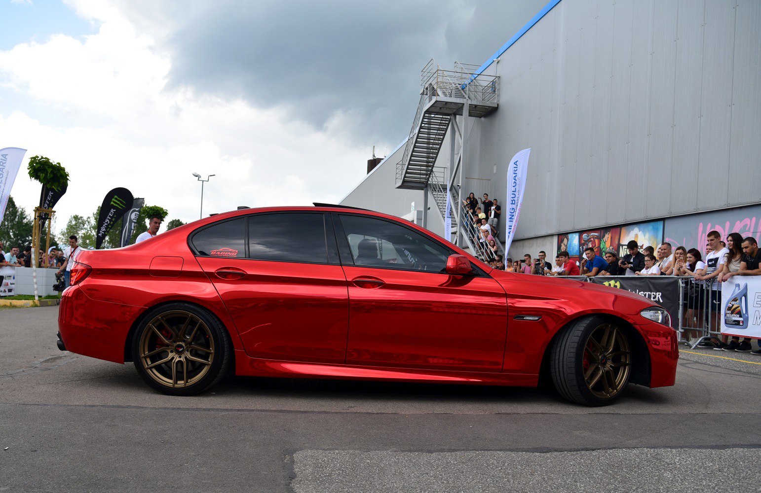 Red sedan with bronze multi-spoke wheels and tinted windows
