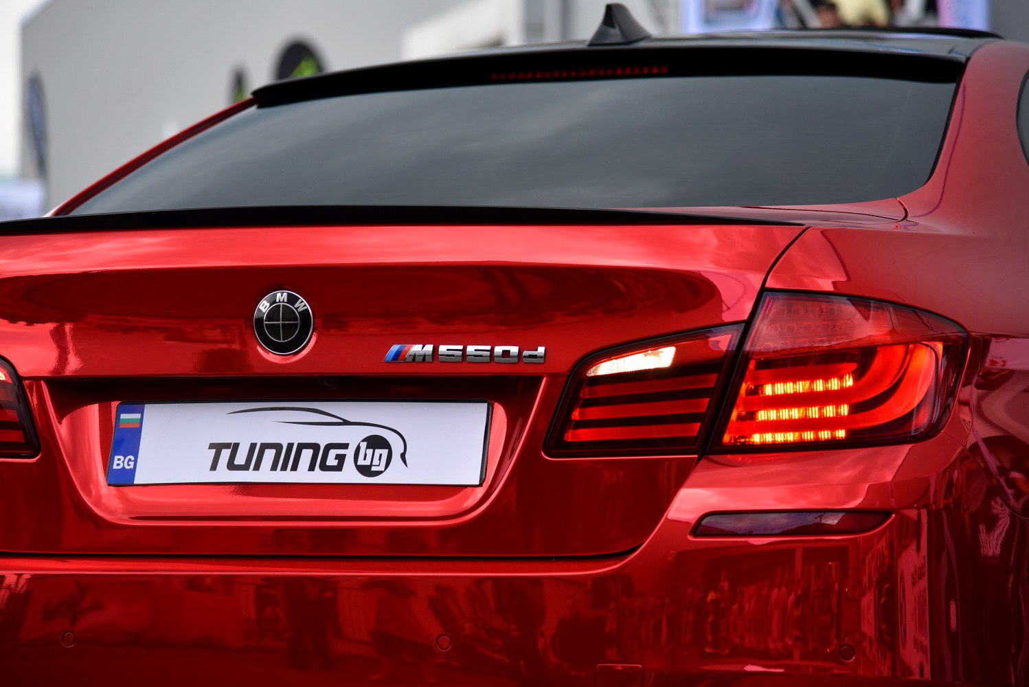 Close-up of rear tail light and trunk badge on a glossy red sedan