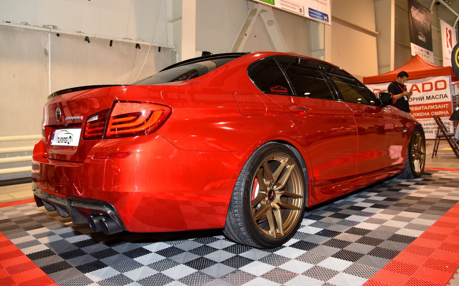 Glossy red sedan with bronze alloy wheels and dual exhaust