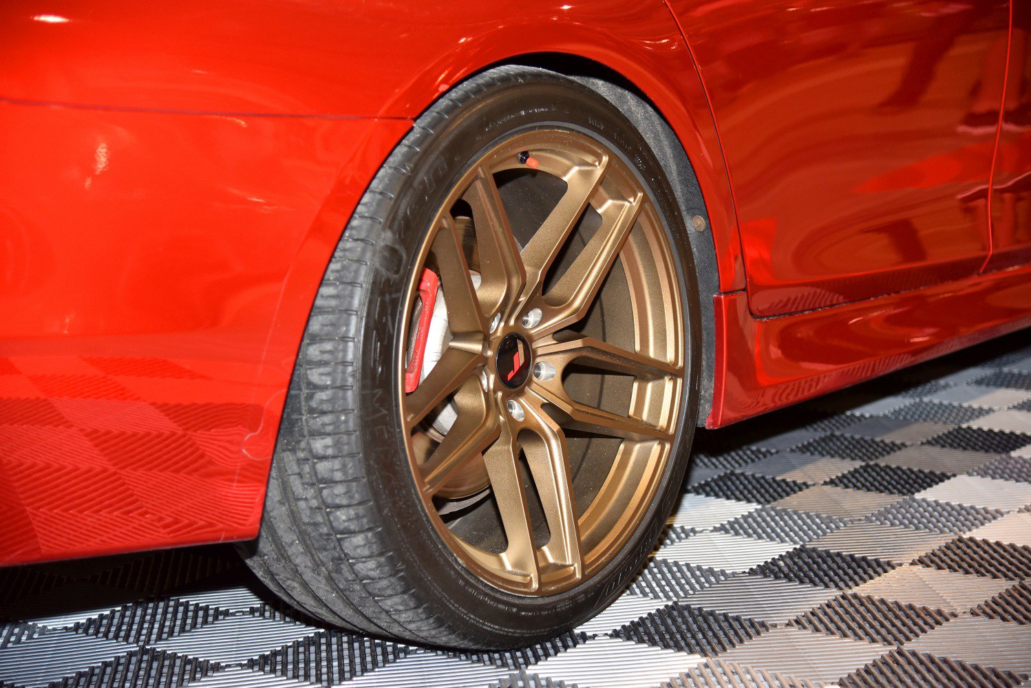 Close-up of bronze alloy wheel with tire and brake on red vehicle