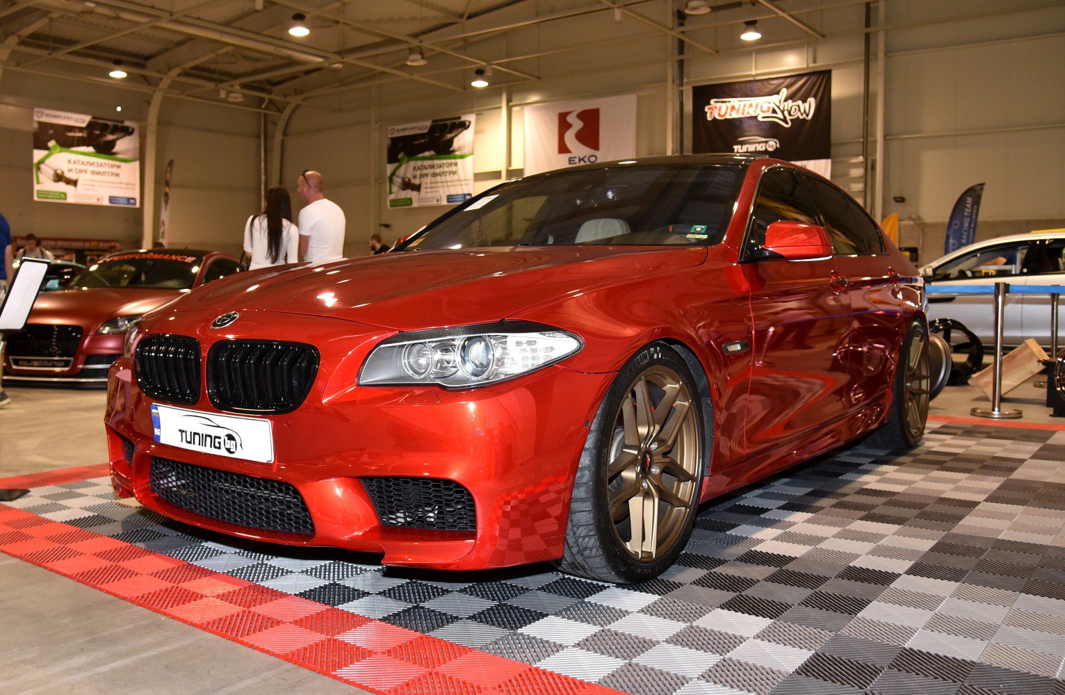 Red sedan with aggressive front grille and bronze alloy wheels