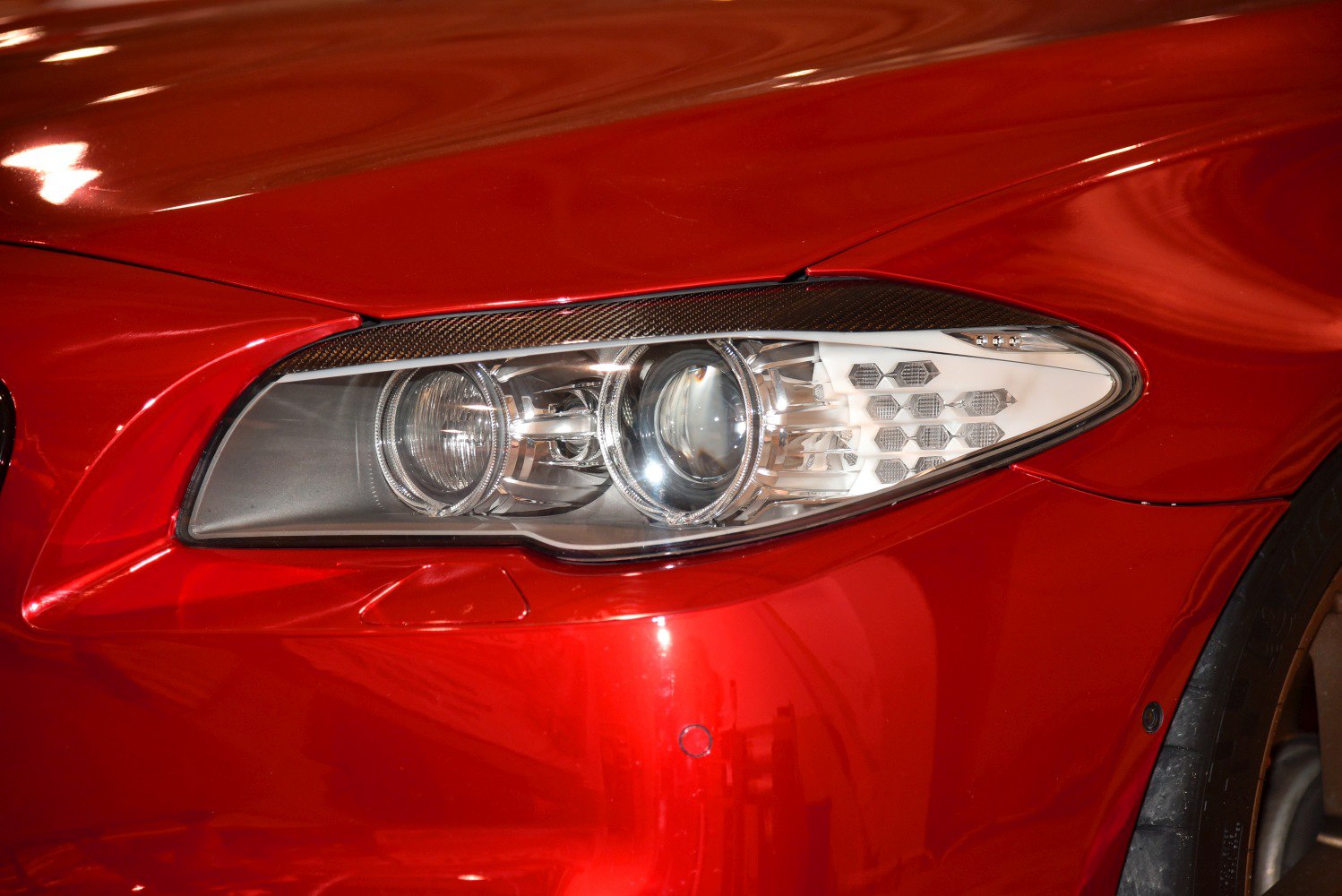 Close-up of a modern car projector headlight with hexagonal lighting elements.