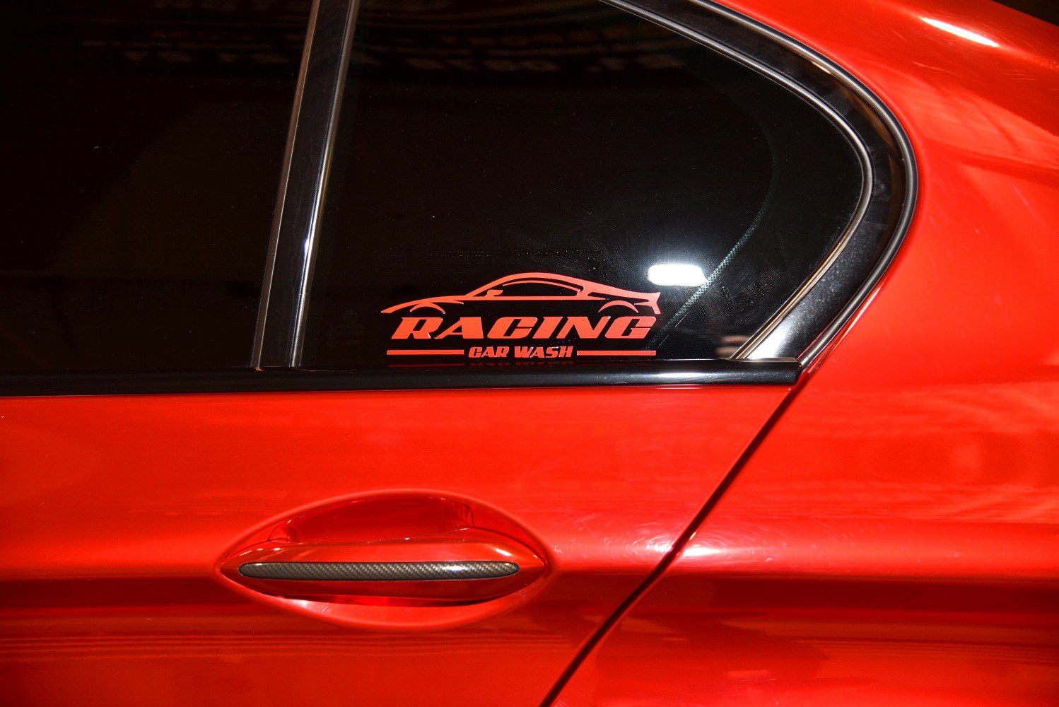 Red car door handle with racing decal on tinted window