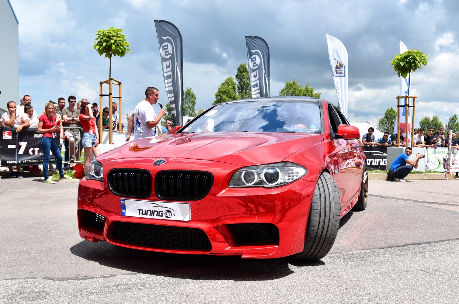 Close-up of front grille, headlights, and wide tires on a red sedan