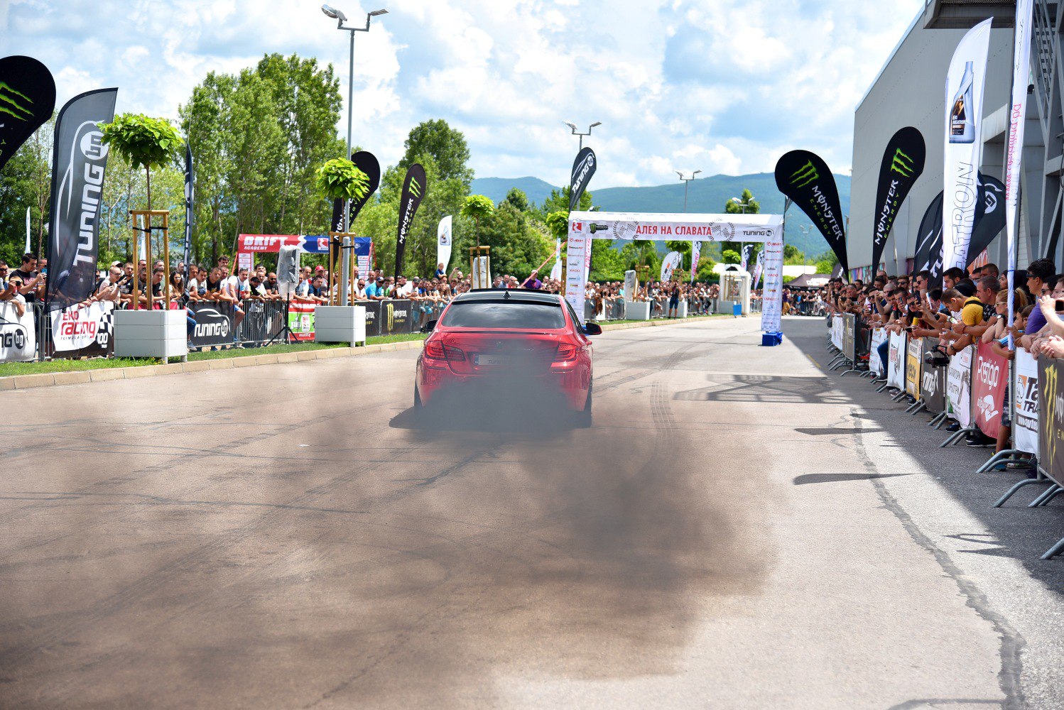Rear view of red car emitting dense exhaust smoke during drift.
