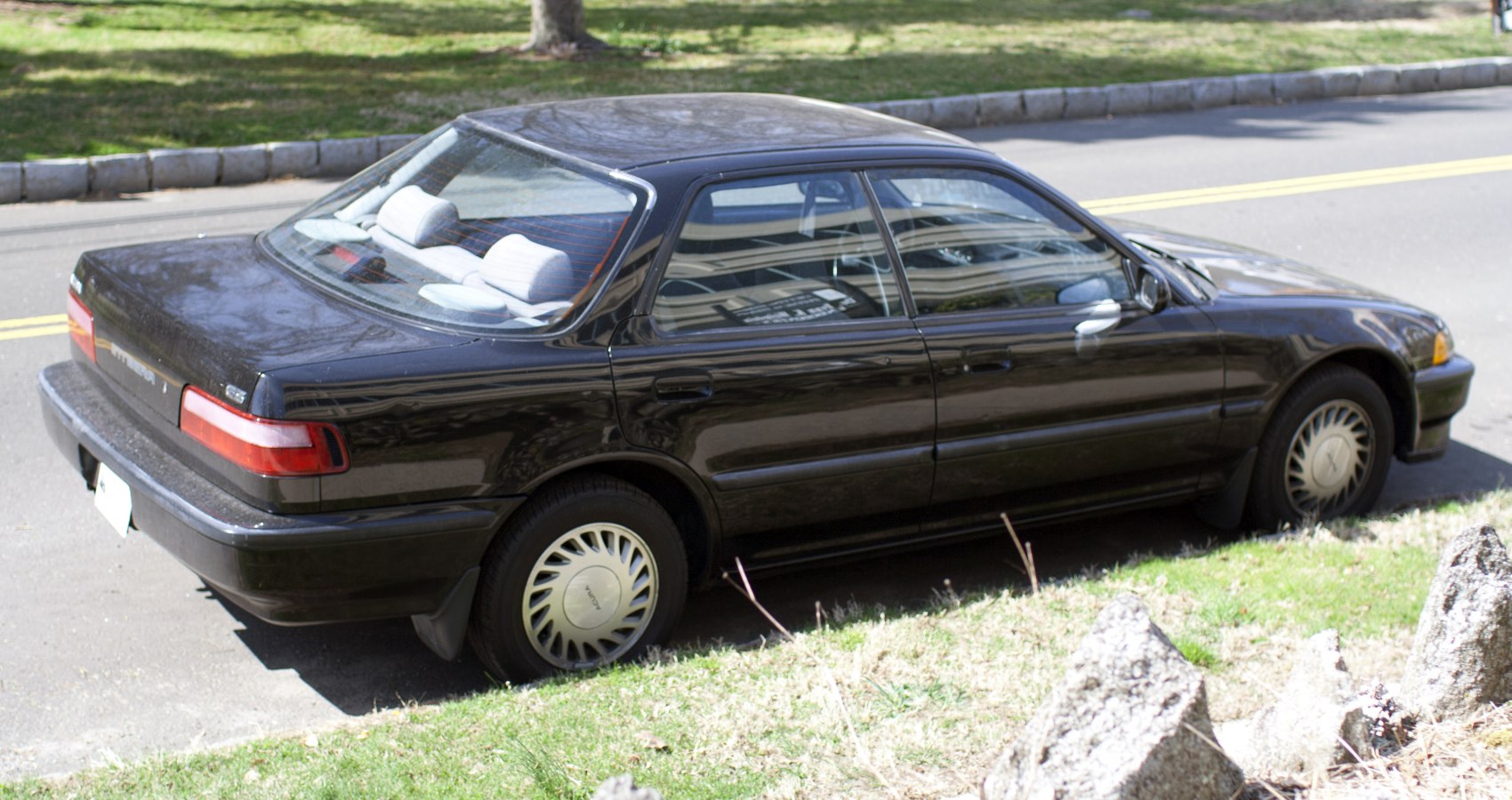 Black 1990 sedan side and rear view with alloy wheels.