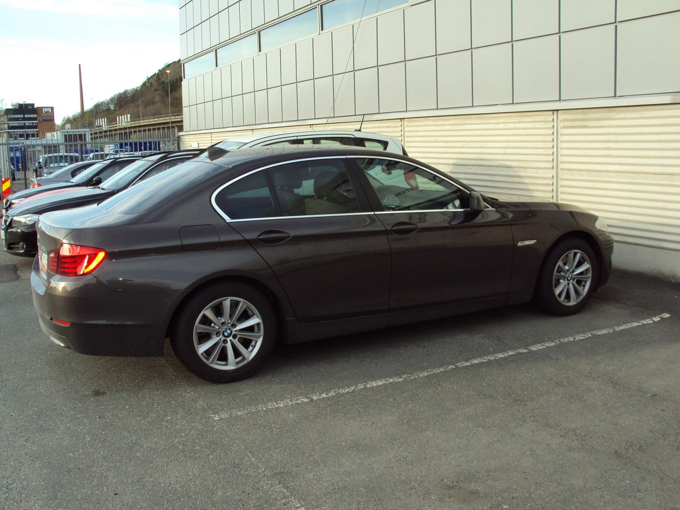Side profile of a mid-size luxury sedan with alloy wheels parked beside a building