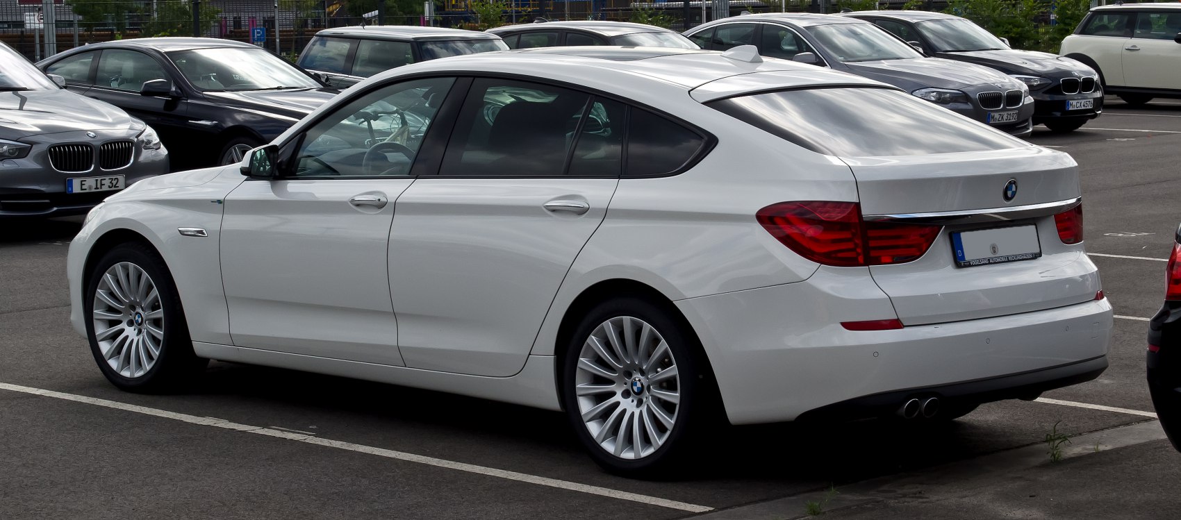 Side and rear profile of a white luxury sedan with distinctive rear lights and sleek body lines