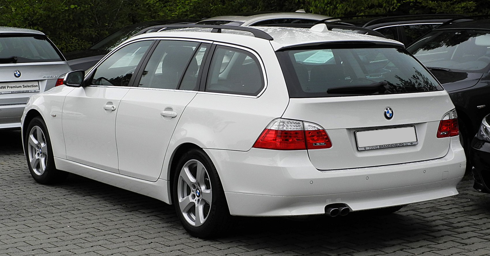 White mid-2000s wagon with roof rails and dual exhaust