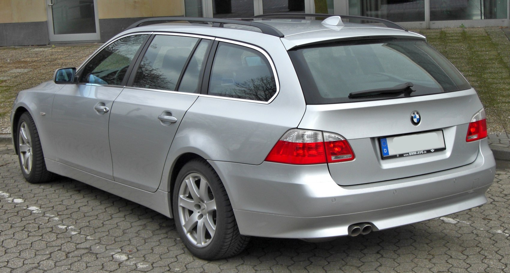 Silver touring car rear side view with dual exhaust and roof rails