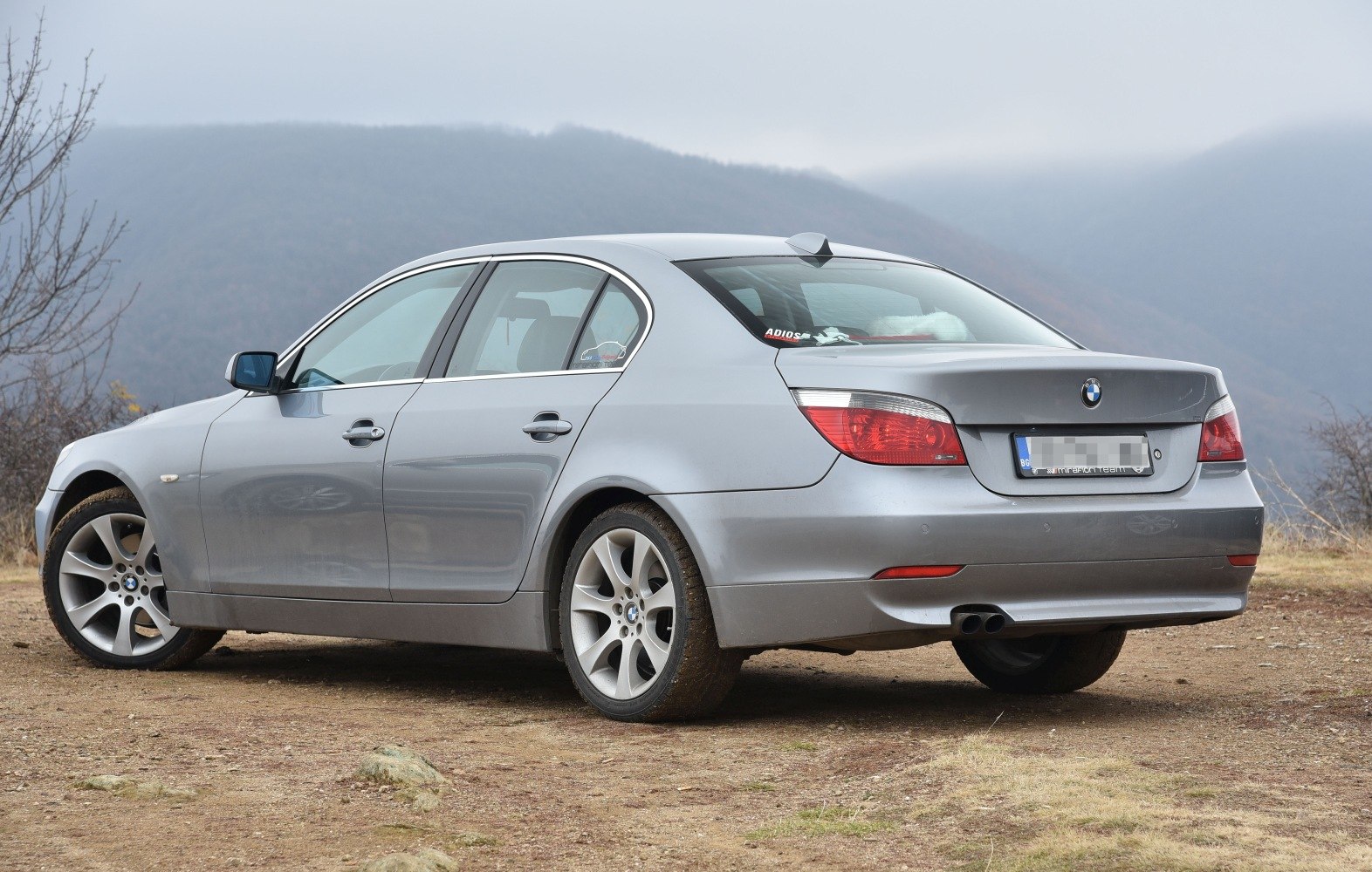 Silver sedan rear side with alloy wheels on dirt terrain