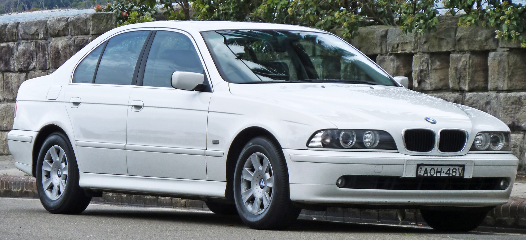 Front side view of white sedan with quad headlights and kidney grille