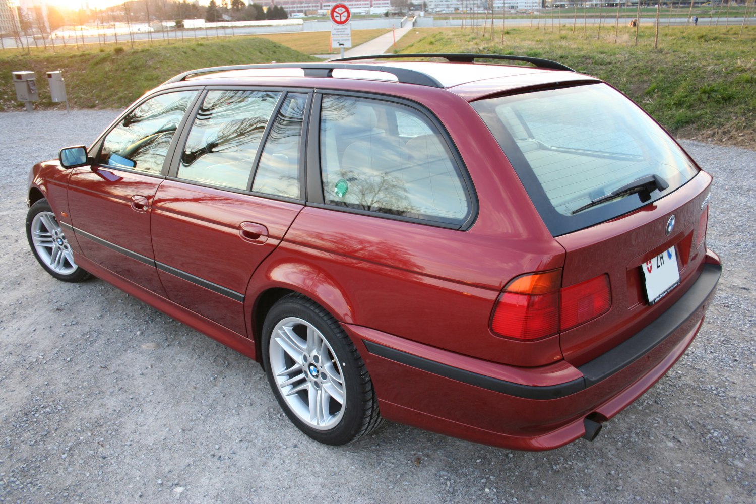 Rear side view of red estate with roof rails and alloy wheels