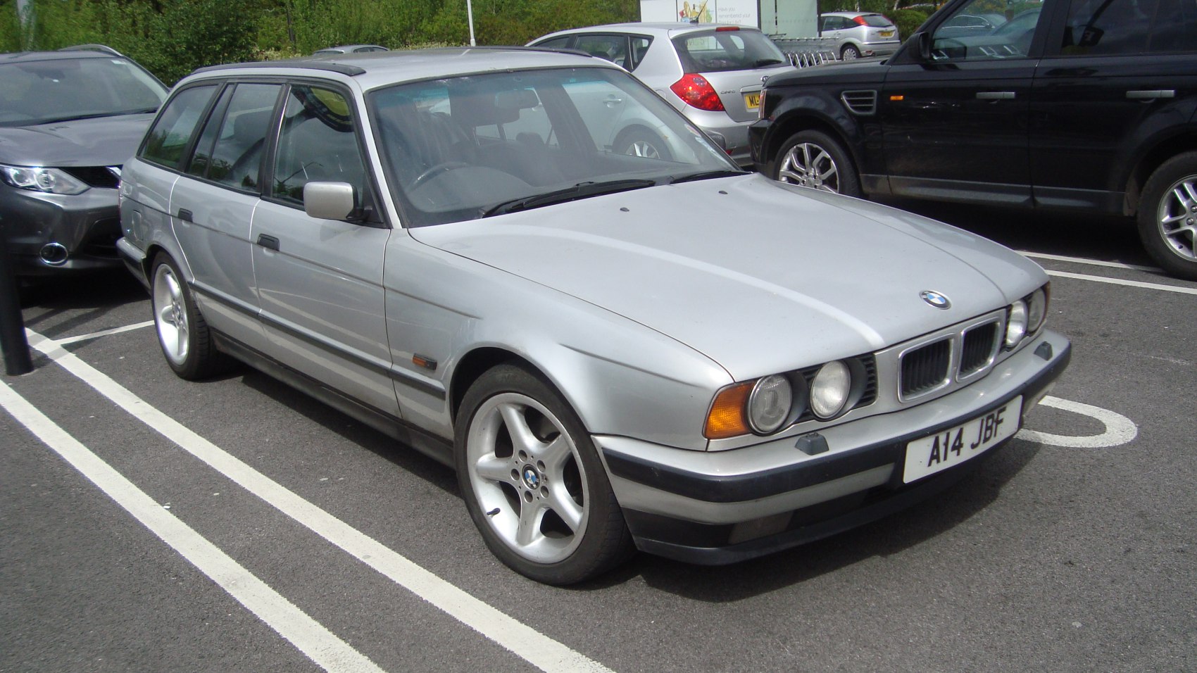 Silver station wagon with dual round headlights, alloy wheels, and roof rails