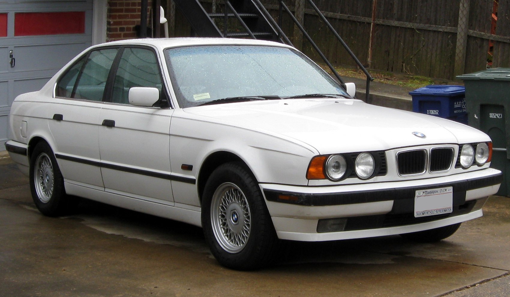 White four-door sedan with dual round headlights and mesh wheels
